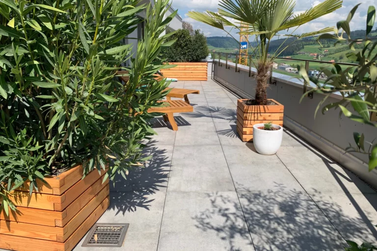 Verschieden große Pflanzkästen aus Holz stehen bepflanzt auf einer privaten Terrasse