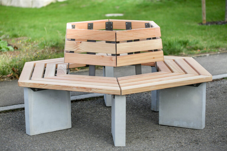Met en avant le banc intégré dans une place ou un parc, démontrant son design contemporain et sa capacité à s’adapter à différents types d’espaces extérieurs.