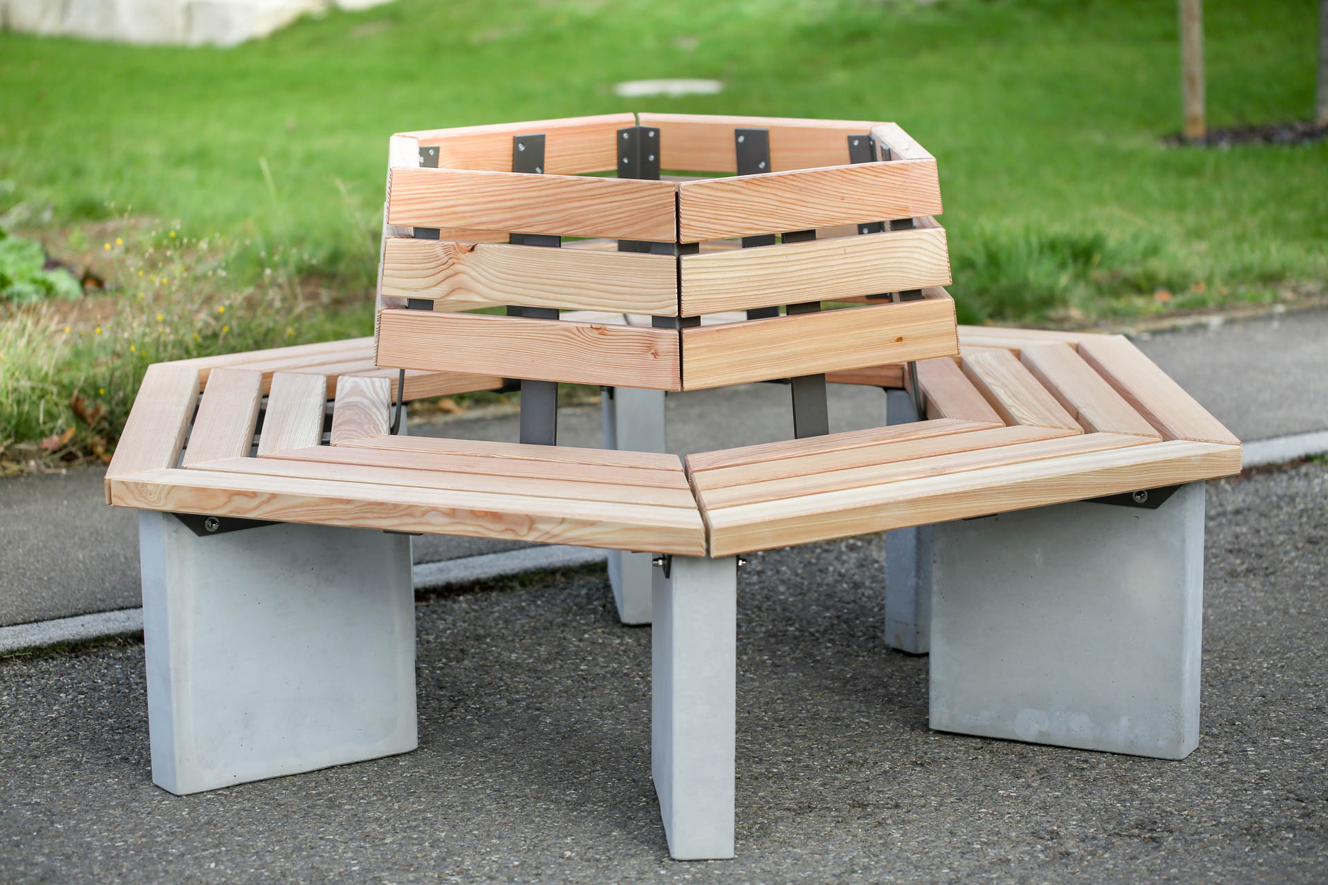 Met en avant le banc intégré dans une place ou un parc, démontrant son design contemporain et sa capacité à s’adapter à différents types d’espaces extérieurs.