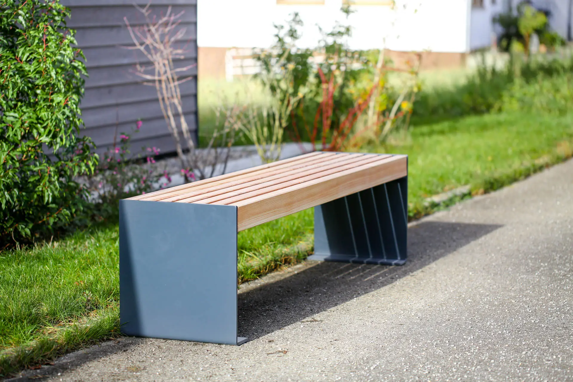 Außenbank aus Metall und Holz steht an öffentlichem Weg