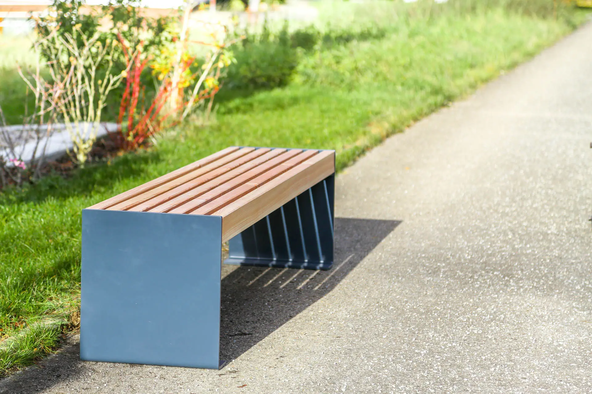 Außenbank aus Metall und Holz steht an öffentlichem Weg