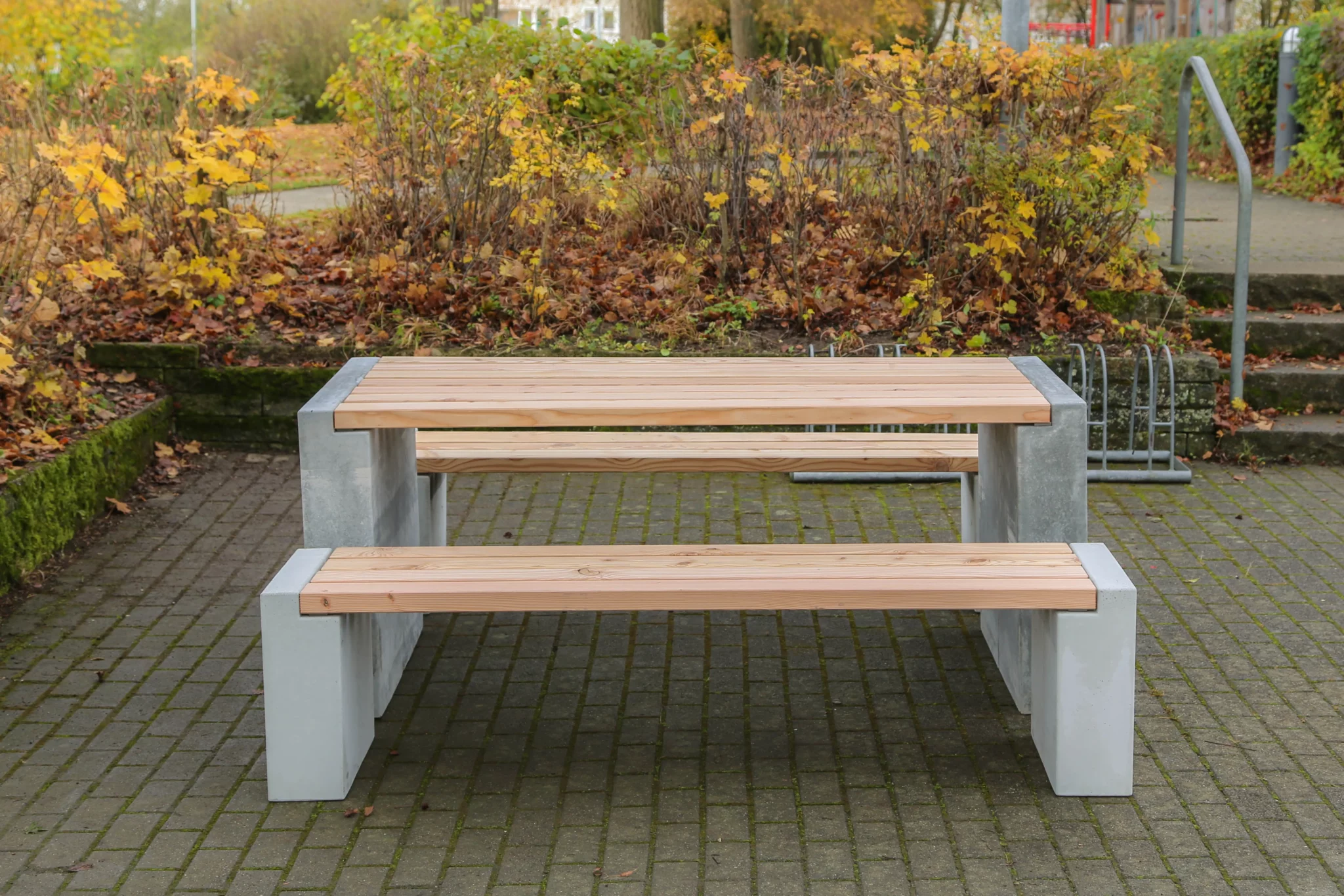 Massiver Tisch aus Sichtbeton und Lärchenholz steht auf öffentlichem Platz