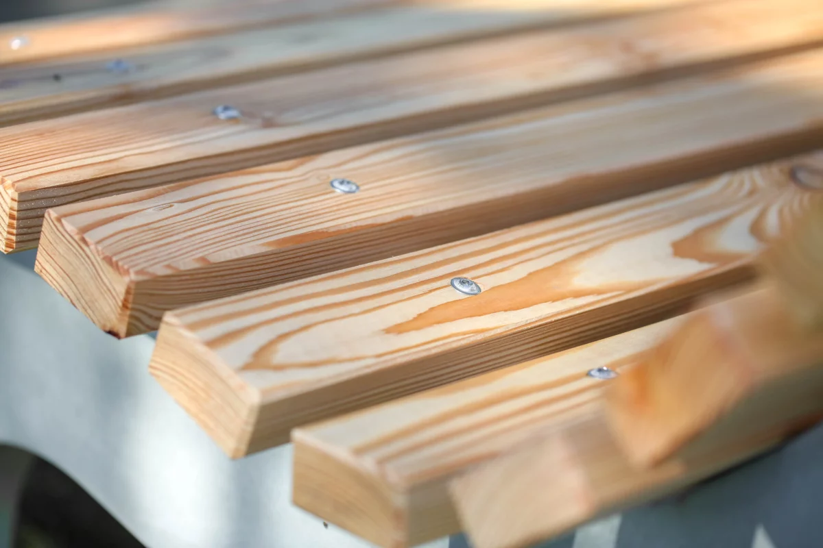 Wellenliege aus Beton und Lärchenholz steht in einem begrünten Außenbereich