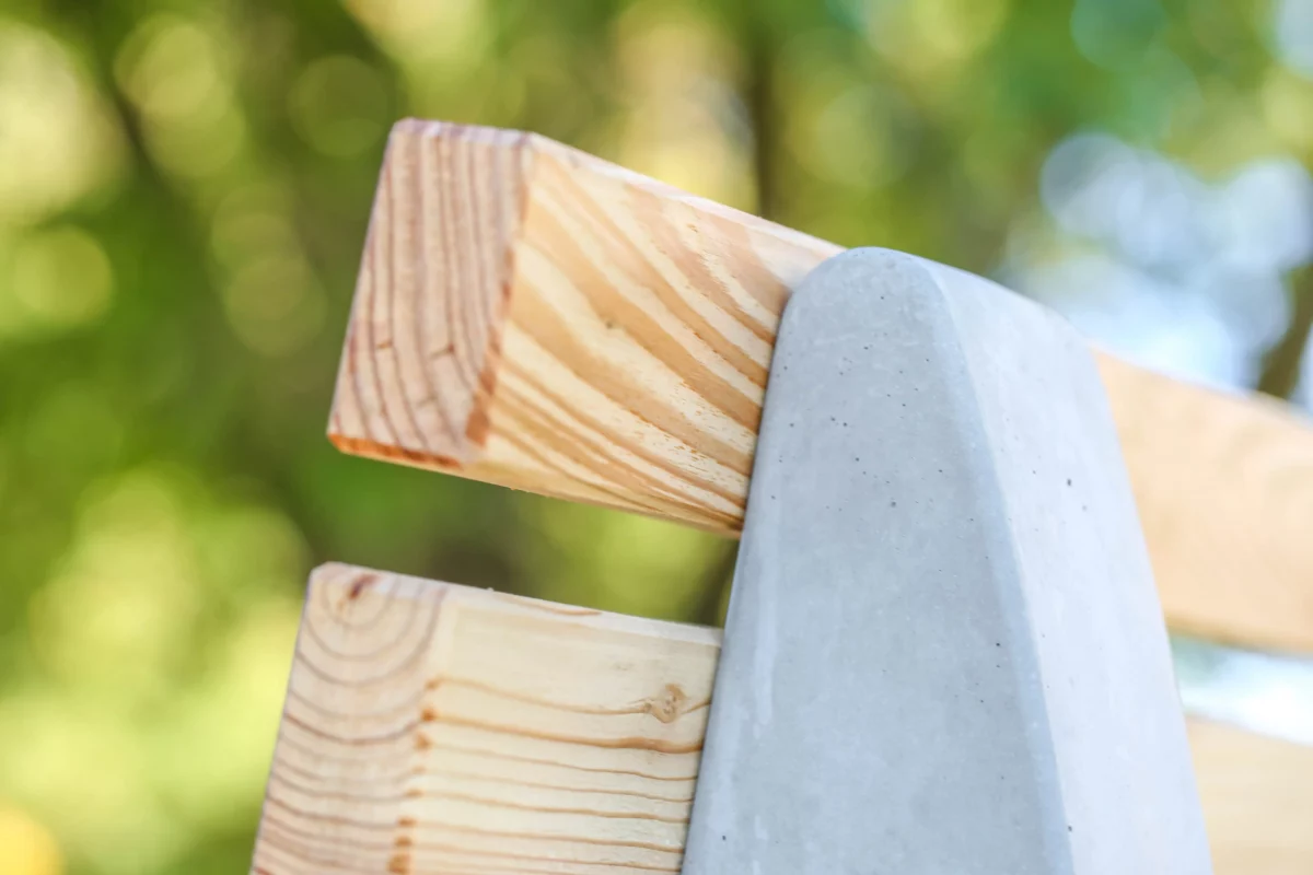 Wellenliege aus Beton und Lärchenholz steht in einem begrünten Außenbereich