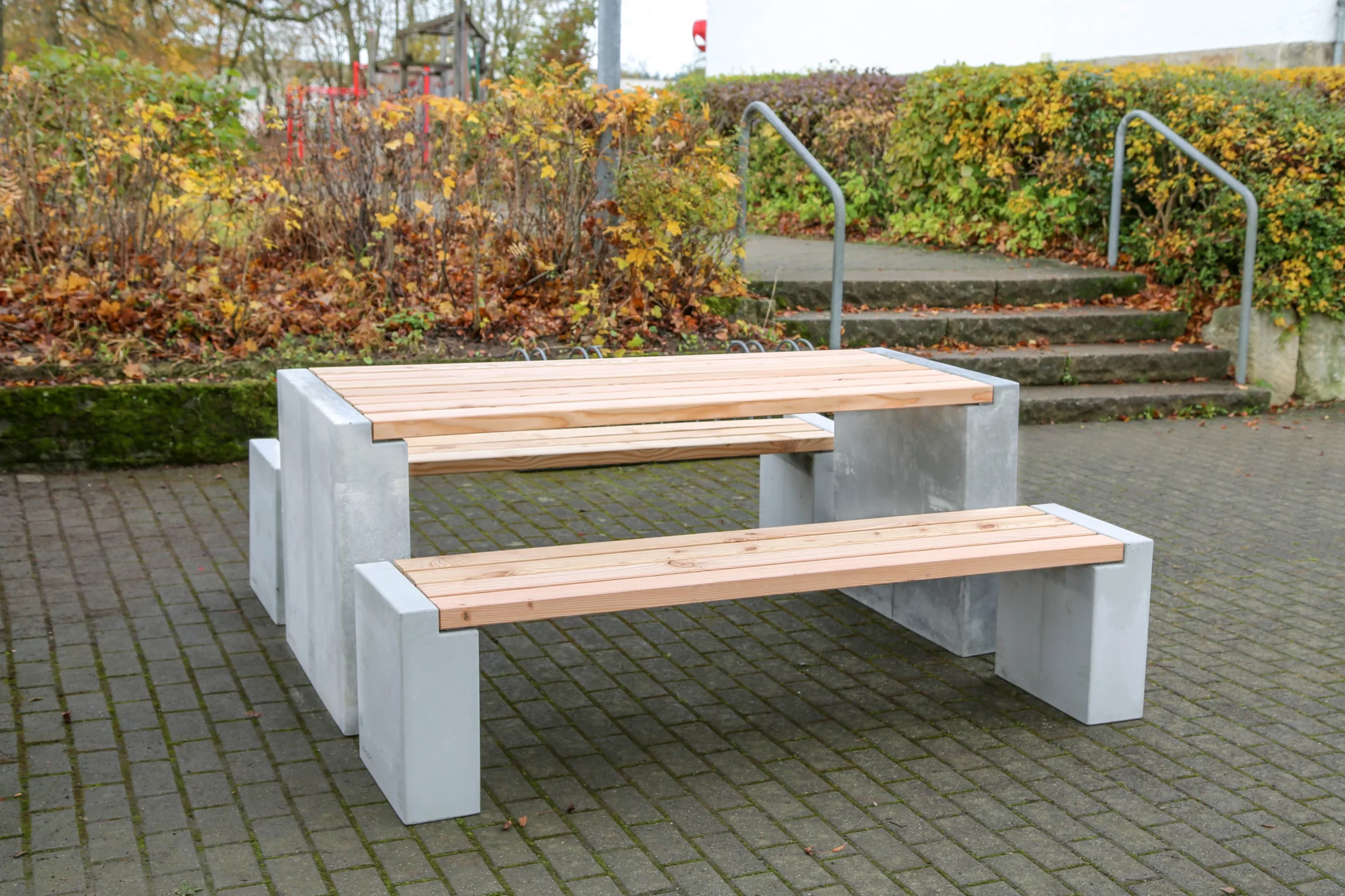 Massiver Tisch aus Sichtbeton und Lärchenholz steht auf öffentlichem Platz