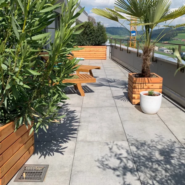 Verschieden große Pflanzkästen aus Holz stehen bepflanzt auf einer privaten Terrasse