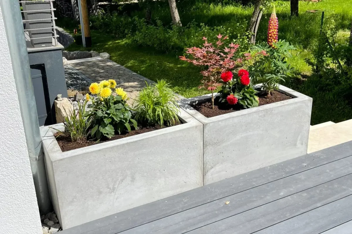 Bunt bepflanzter Trog aus Beton steht in öffentlichem Bereich