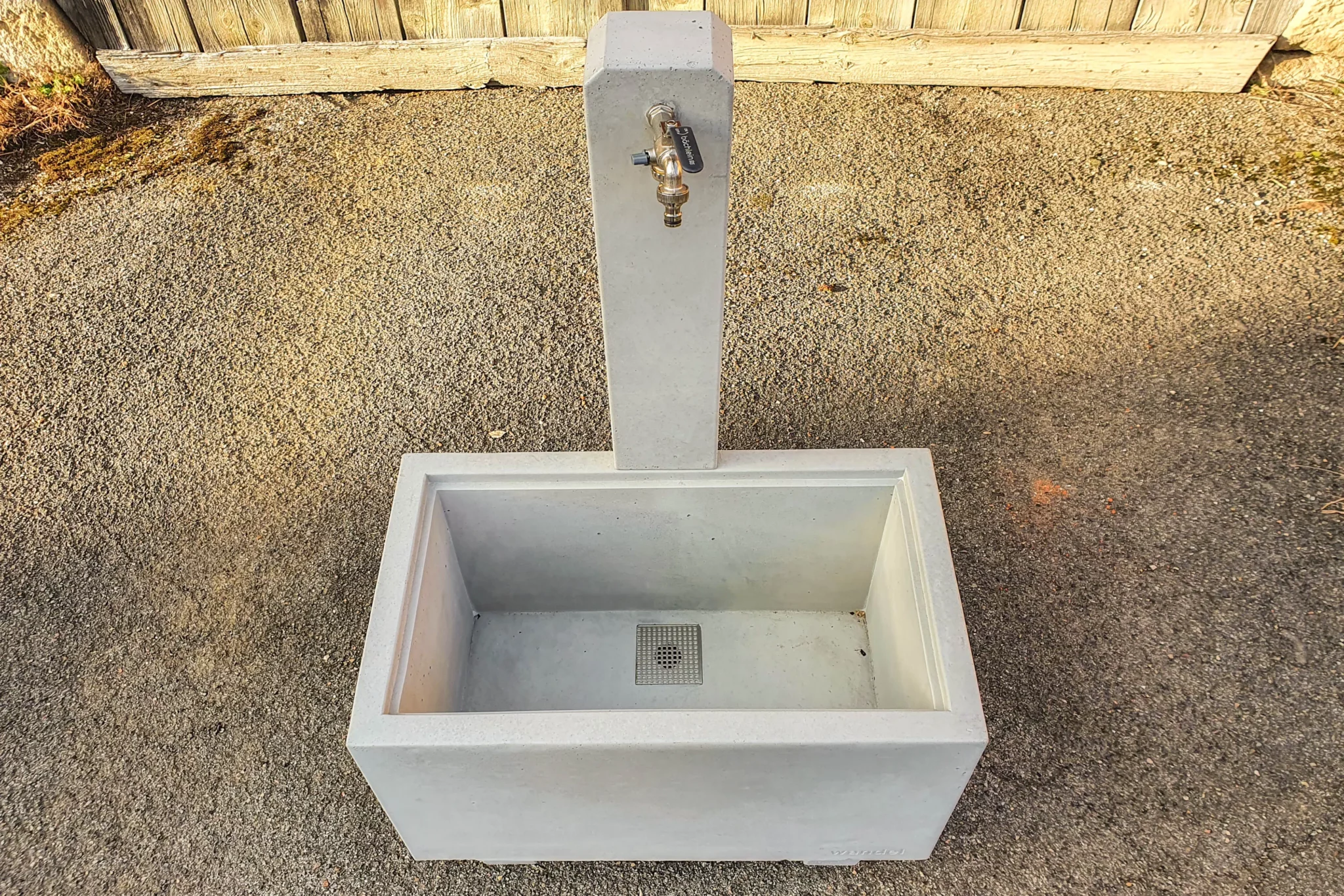 Zapfbrunnen aus Sichtbeton steht auf einem öffentlichen Gelände