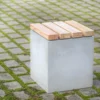 Hocker aus Beton mit Sitzauflage aus Lärchenholz steht auf öffentlicher Grünanlage