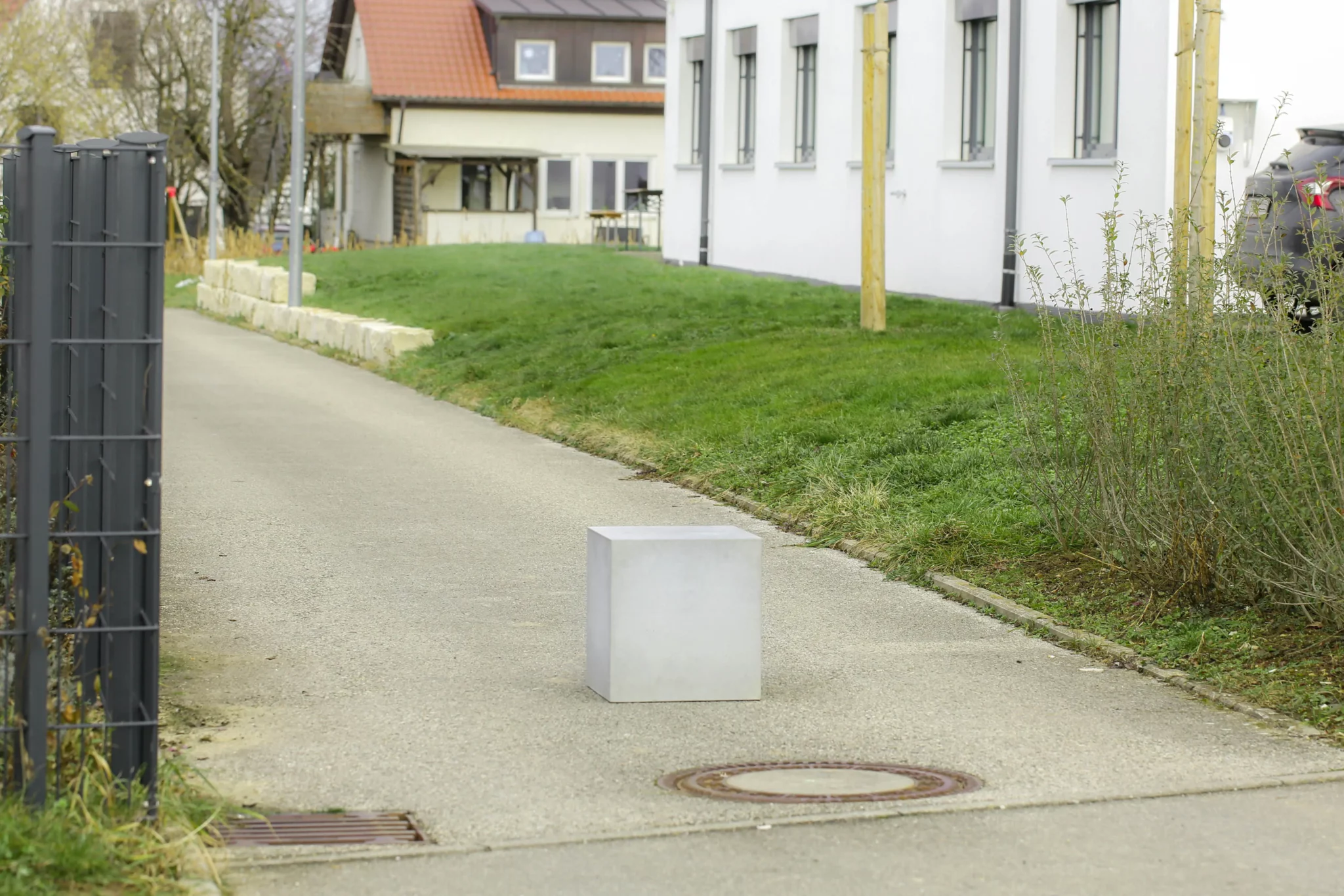 Massiver Poller aus Sichtbeton steht auf öffentlichem Weg zur Durchfahrtsbeschränkung