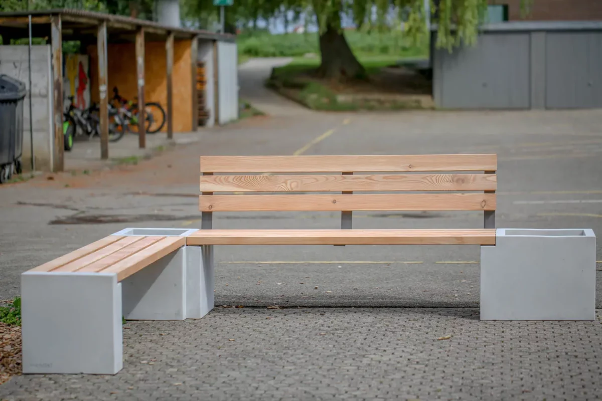 Eckbank aus Beton und Lärchenholz steht auf öffentlichem Platz