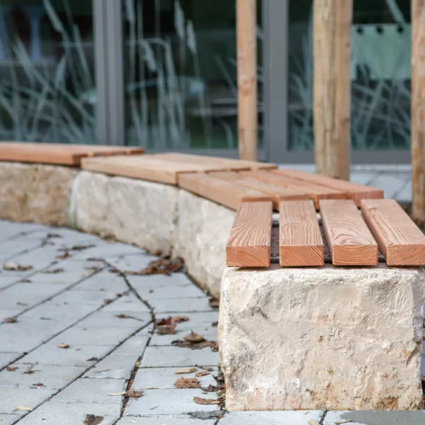 Mauerauflage aus Lärchenholz platziert auf Steinmauer vor öffentlichem Gebäude