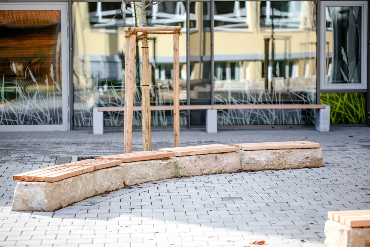 Mauerauflage aus Lärchenholz platziert auf Steinmauer vor öffentlichem Gebäude