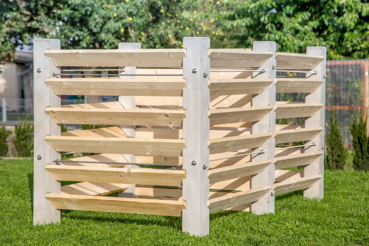 Komposter aus Beton und Lärchenholz steht auf einer grünen Wiese