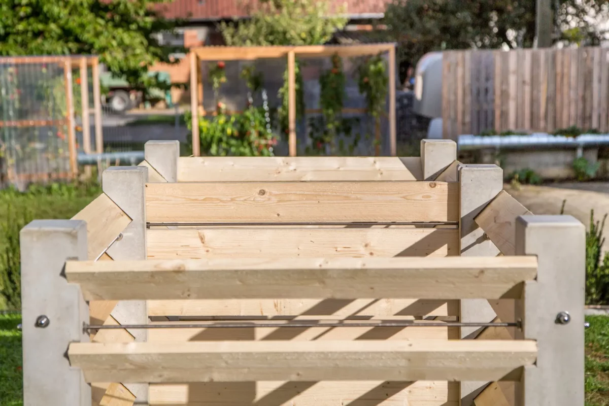 Komposter aus Beton und Lärchenholz steht auf einer grünen Wiese