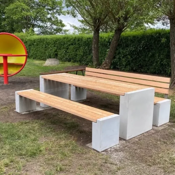 Sitzgruppe aus Beton und Lärchenholz steht auf einem Spielplatz