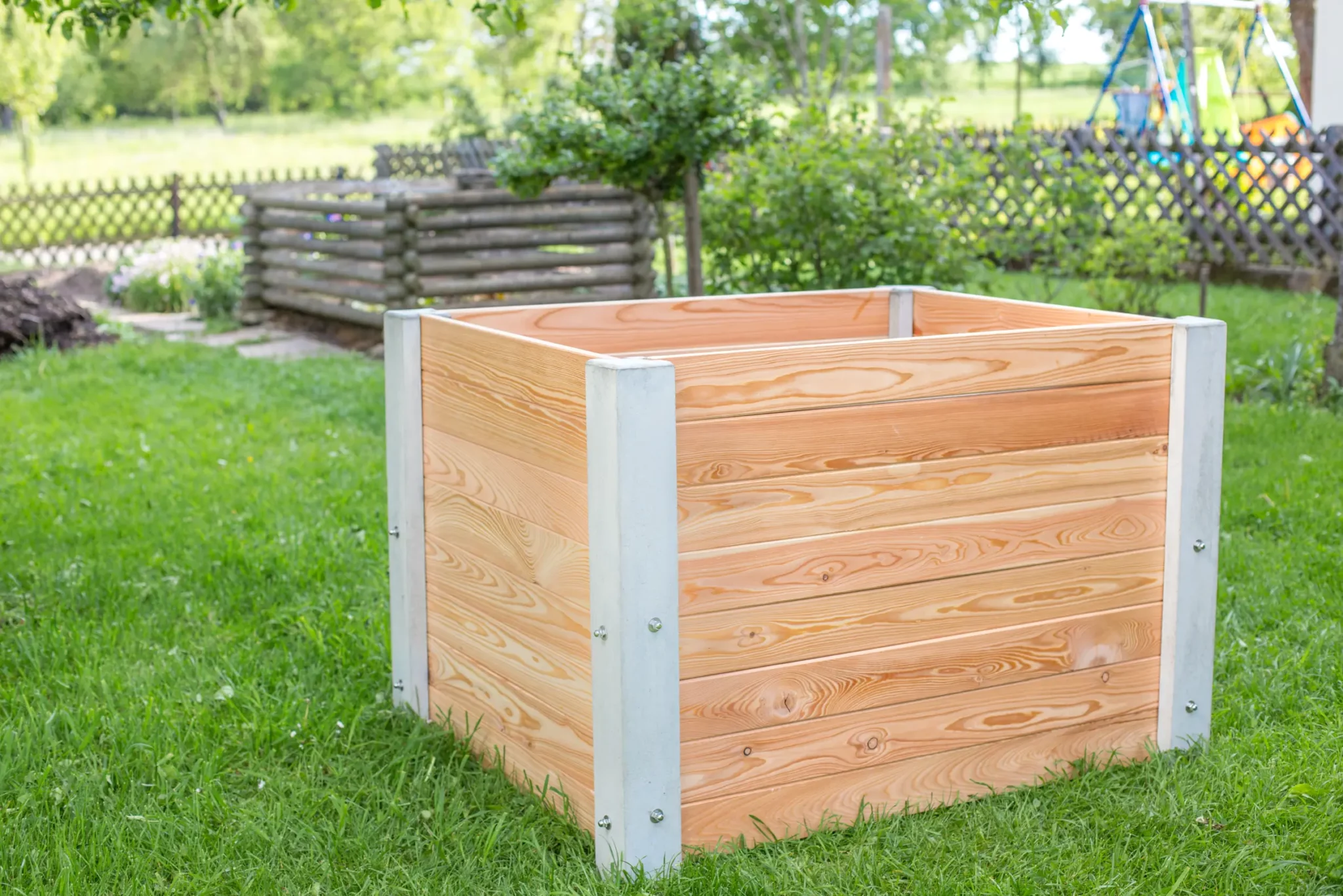Hochbeet aus Beton und Lärchenholz steht auf Rasenfläche