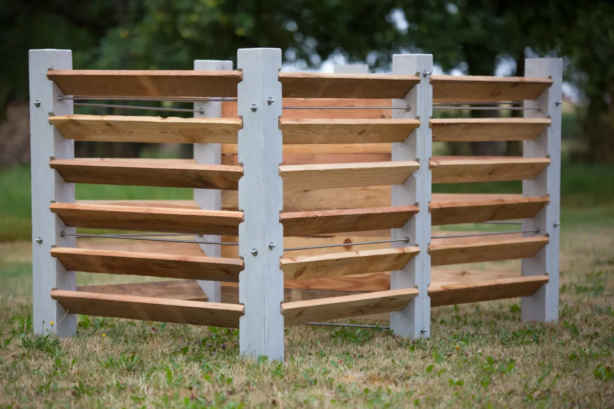 Komposter aus Beton und Lärchenholz steht auf einer grünen Wiese