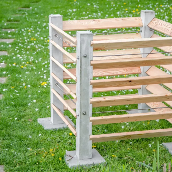Komposter aus Beton und Lärchenholz steht auf einer grünen Wiese