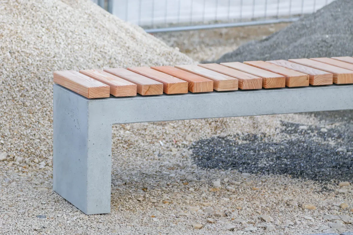 Massive Sitzbank aus Sichtbeton, optional mit Sitzauflage aus Holzdielen, steht in öffentlichem Bereich