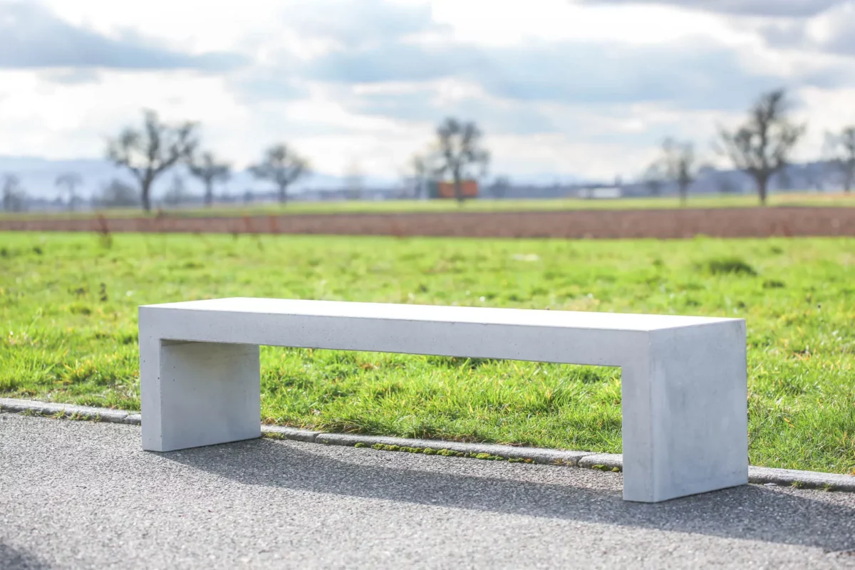 Massive Sitzbank aus Sichtbeton, optional mit Sitzauflage aus Holzdielen, steht in öffentlichem Bereich
