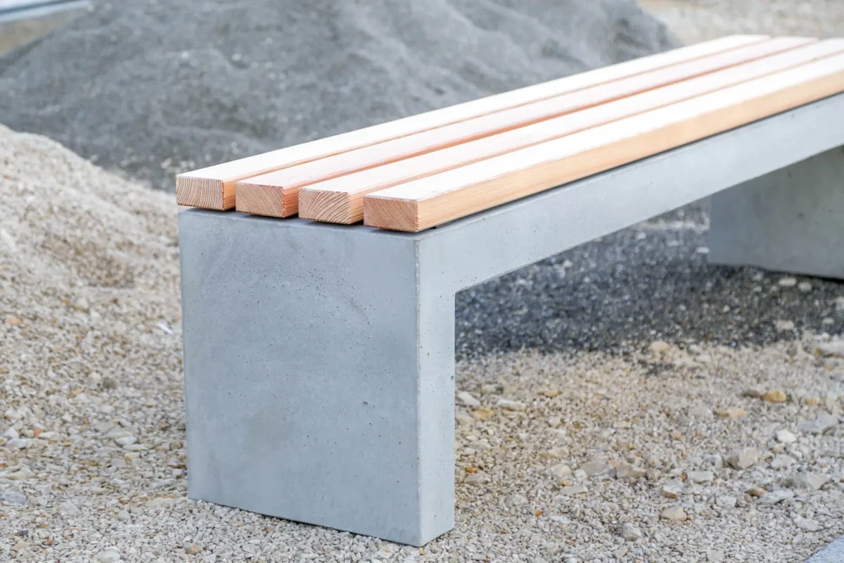 Massive Sitzbank aus Sichtbeton, optional mit Sitzauflage aus Holzdielen, steht in öffentlichem Bereich