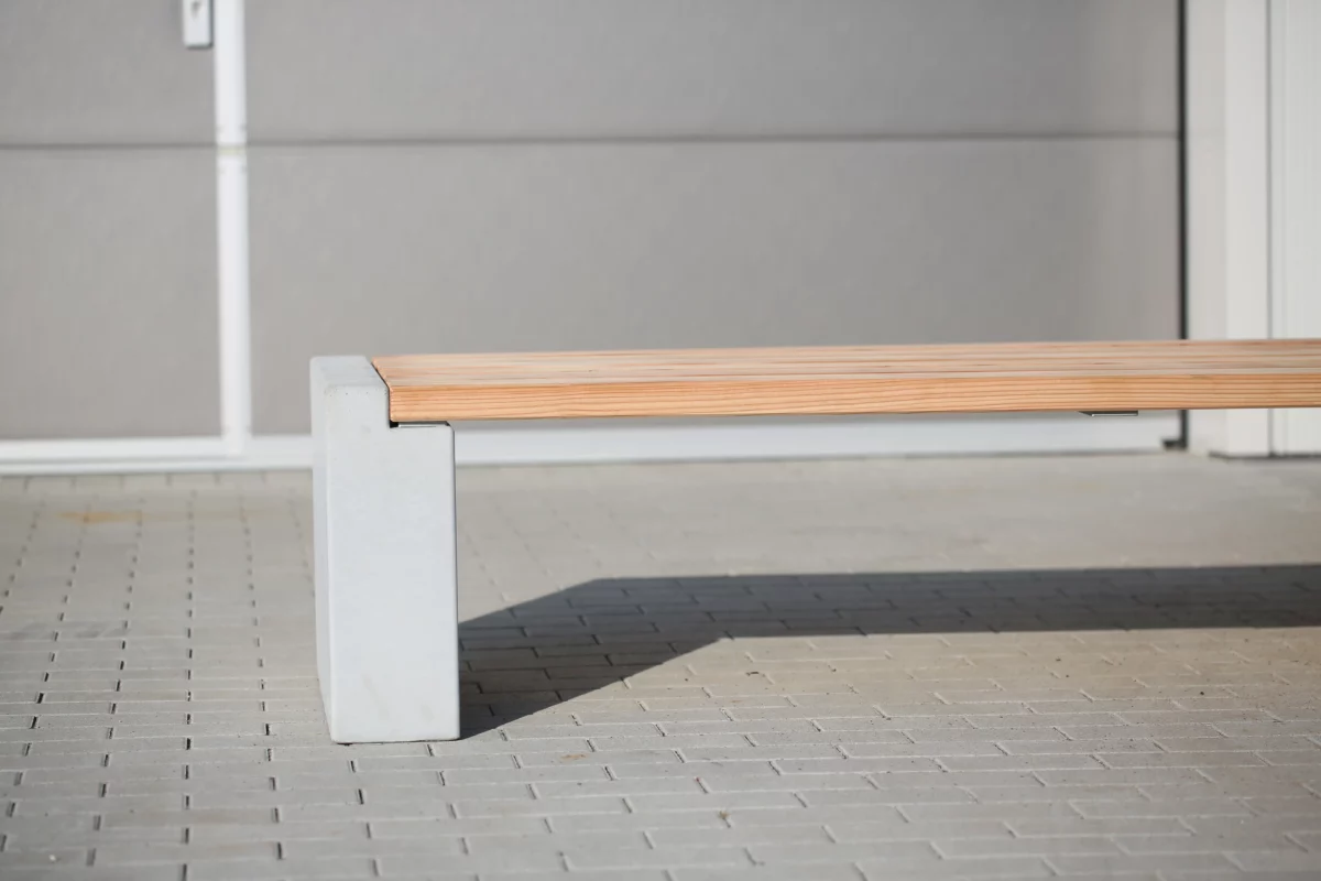 Sitzbank in Überbreite aus Beton und Lärchenholz steht auf einer öffentlichen Fläche