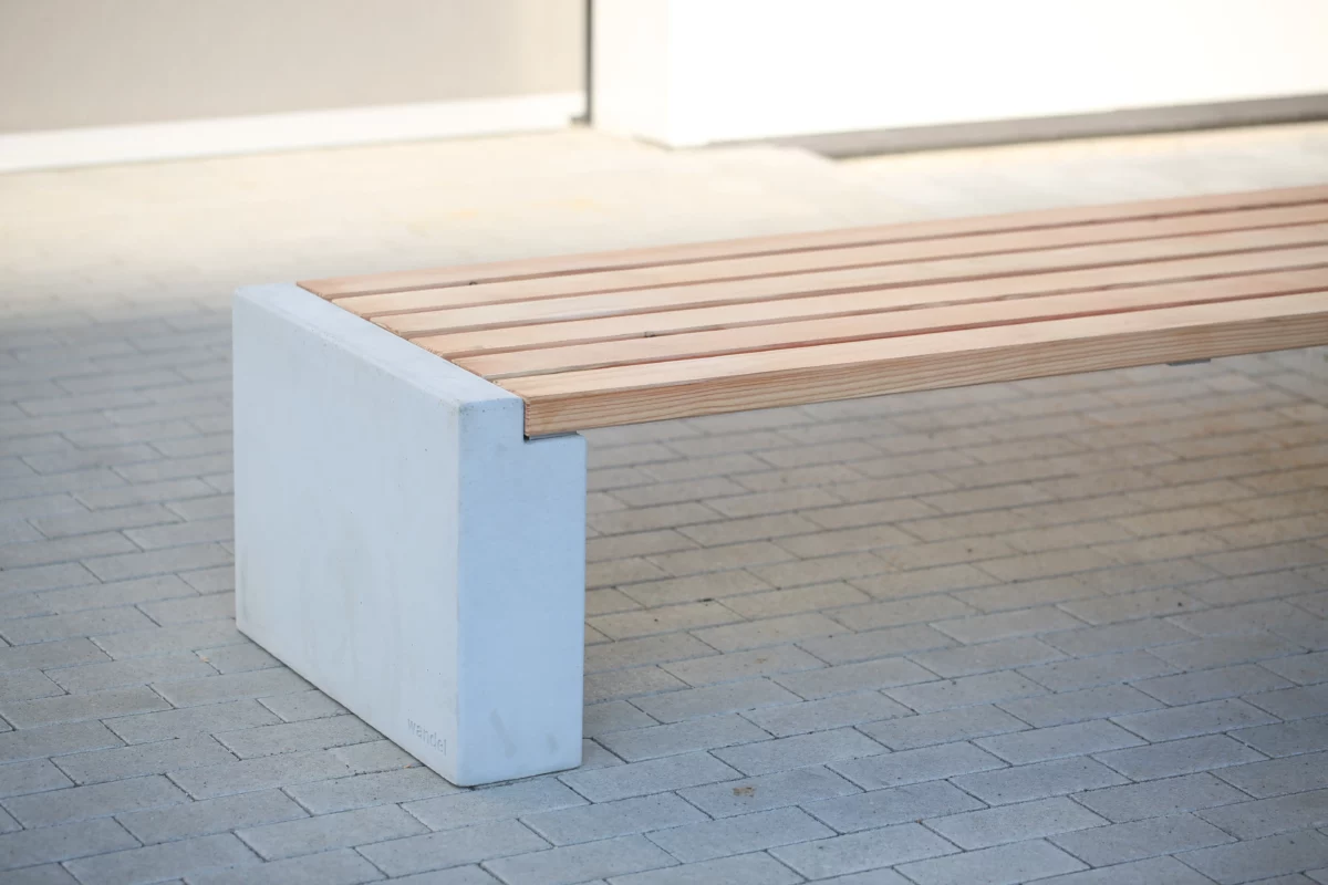 Sitzbank in Überbreite aus Beton und Lärchenholz steht auf einer öffentlichen Fläche