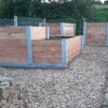 Hochbeet über Ecke aus Lärchenholz und Beton steht in einem privaten Garten mit viel Grün