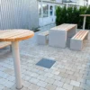 Stehtisch mit Betonfuß zum Einbetonieren und Auflage aus Lärchenholz steht in Mitarbeiterbereich eines Firmengeländes