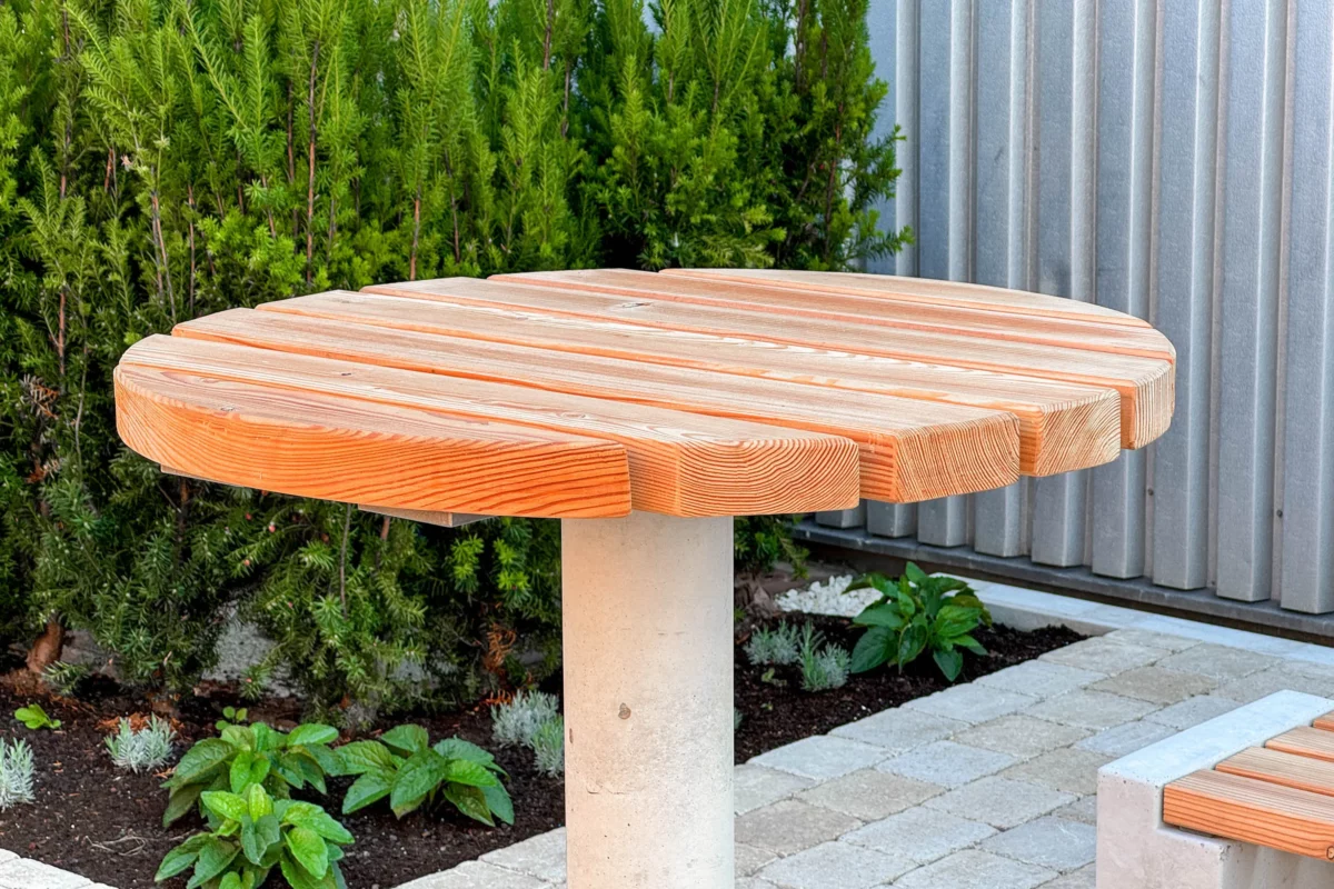 Stehtisch mit Betonfuß zum Einbetonieren und Auflage aus Lärchenholz steht in Mitarbeiterbereich eines Firmengeländes